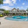 Resort-style pool at Villas at Legacy apartments in Plano, TX, with lush greenery, water features, and lounge seating