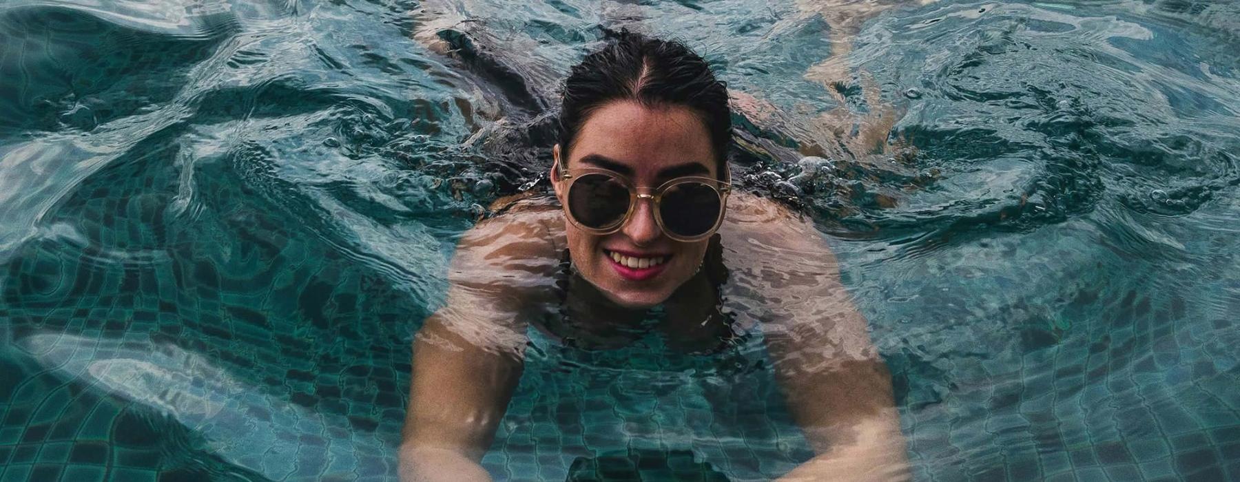 woman with sunglasses swims in pool
