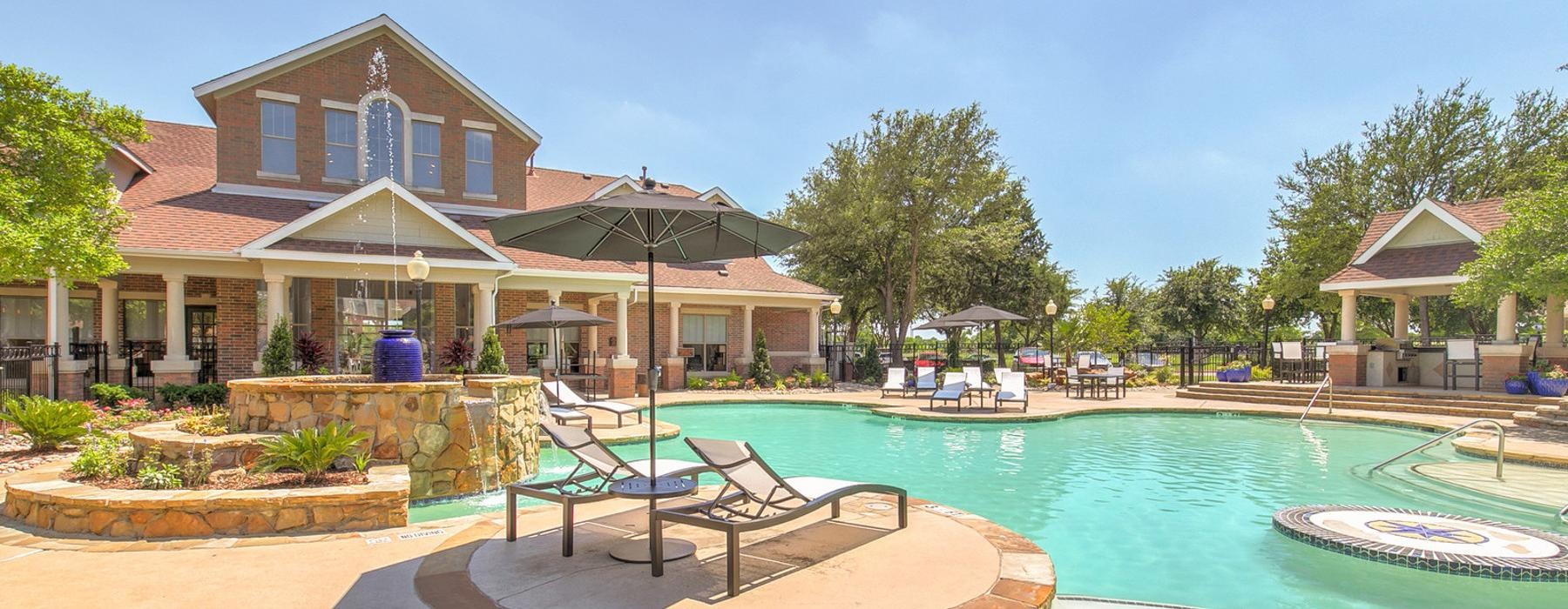 a pool with lounge chairs and lush landscaping